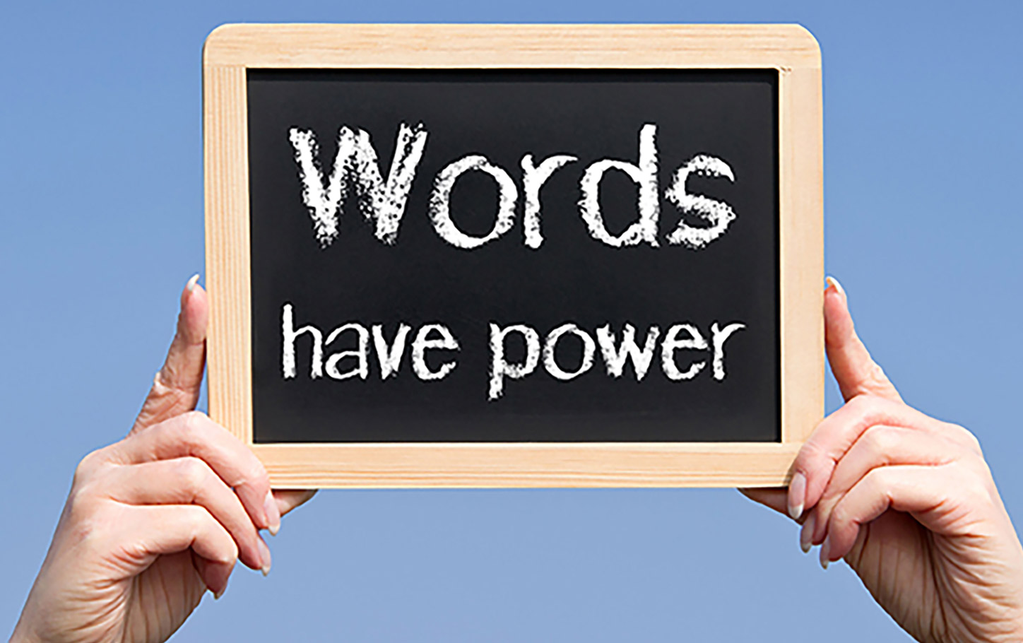 2 hands holding up chalkboard that says "Words Have Power"